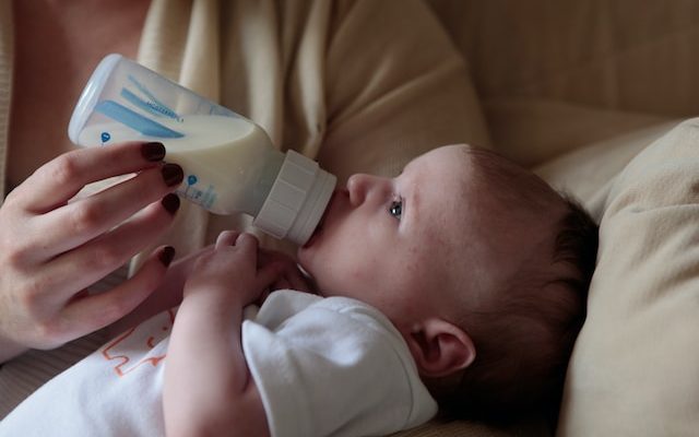 A mother is feeding baby formula to her baby