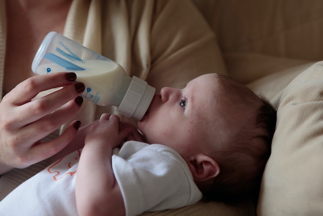 A mother is feeding baby formula to her baby