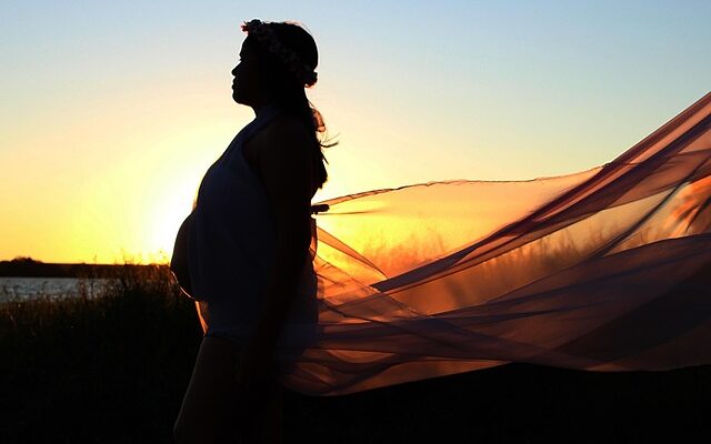 Pregnant woman embracing calm at sunset—managing anxiety through peace and reflection.
