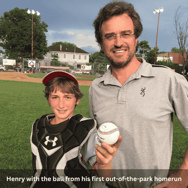 Henry and his father proudly holding the ball from his first out-of-the-park homerun on the baseball field.