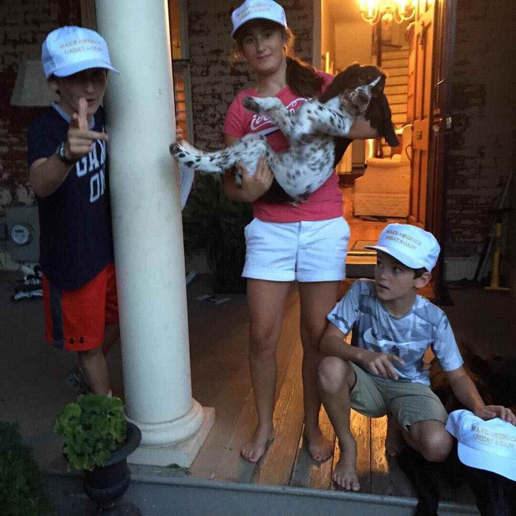 Sam, Lily, and Henry posing with a dog . Sam (left), Lily (middle), and Henry (right) standing, each wearing a "Make America Great Again" hat, with Lily holding a dog. is this version correct?