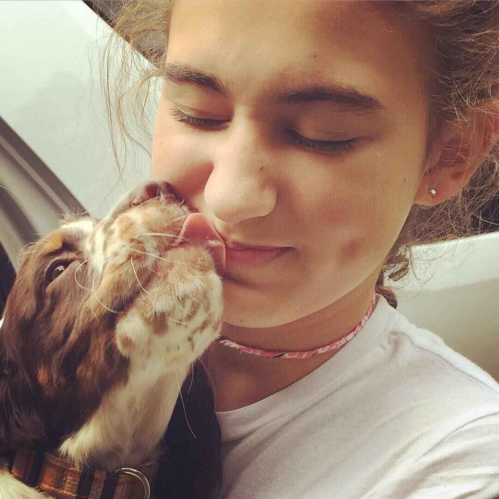 Lily smiles as her puppy gives her a loving kiss after returning home from camp.