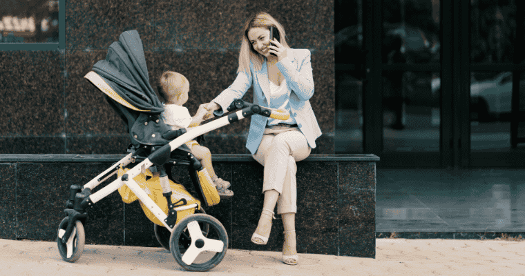 A mother sitting outdoors with her baby in a stroller, highlighting everyday considerations when choosing a baby’s first stroller.