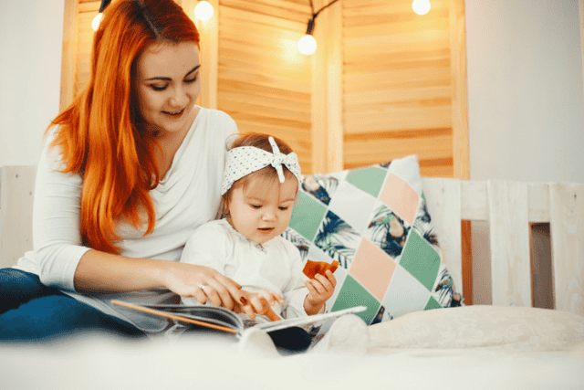 A mother reading a book with her baby, highlighting daily routines that support early learning and first-year developmental milestones.