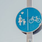 Blue road sign showing pedestrian and bicycle lanes, representing changing city traffic patterns that can influence family daily routines and travel.