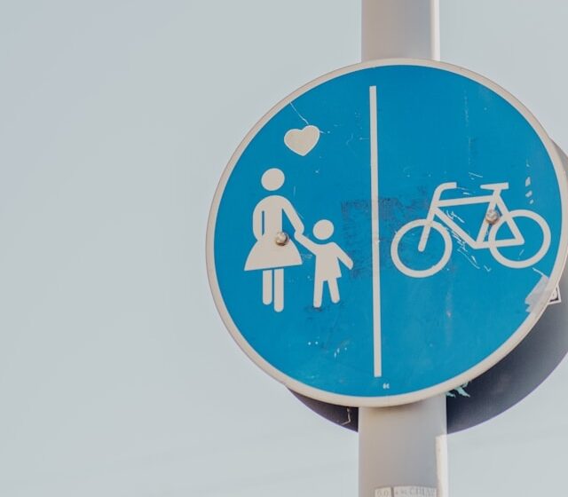 Blue road sign showing pedestrian and bicycle lanes, representing changing city traffic patterns that can influence family daily routines and travel.