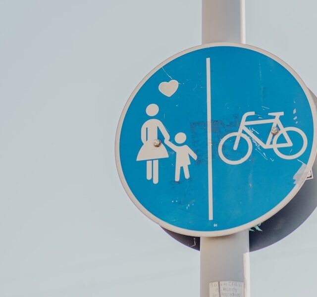 Blue road sign showing pedestrian and bicycle lanes, representing changing city traffic patterns that can influence family daily routines and travel.