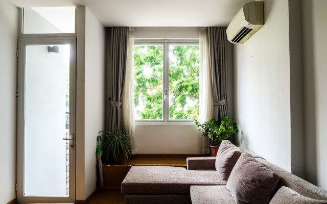 Living room with a cozy sofa, indoor plants, and a large window with curtains.